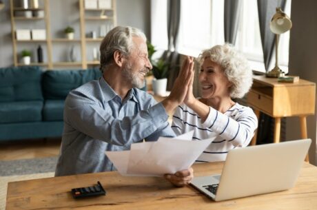 Employer-provided health insurance image of senior man and woman giving high-five.