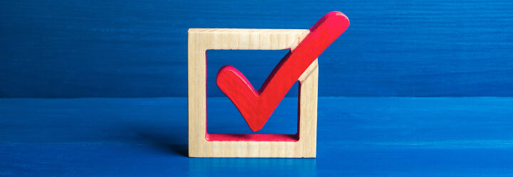 Implementation concept photo depicts a wood square checkbox with a red wood check marking it.